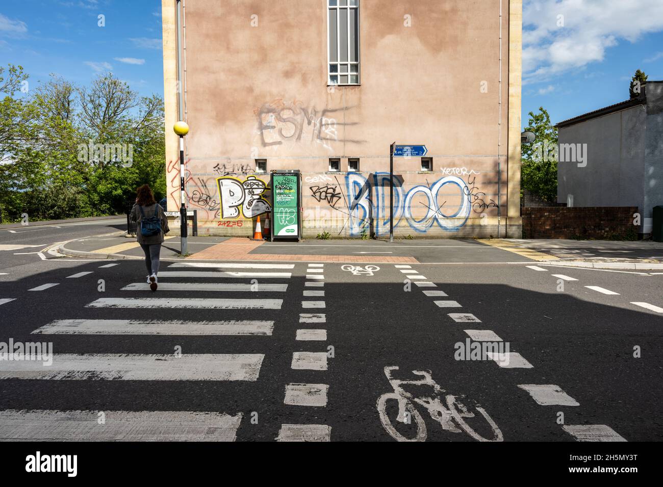 Un piéton traverse une rue en utilisant un cycle parallèle et une traversée en zébrée sur la voie verte de Filwood à Bedminster, Bristol. Banque D'Images