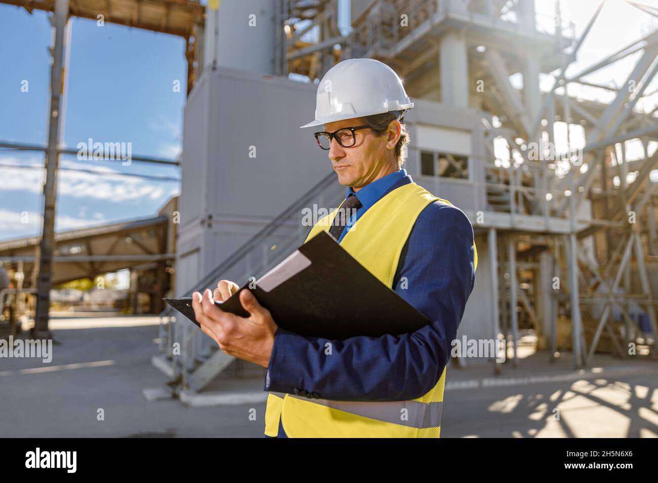 Homme ingénieur écrivant des documents à l'extérieur à l'usine Banque D'Images