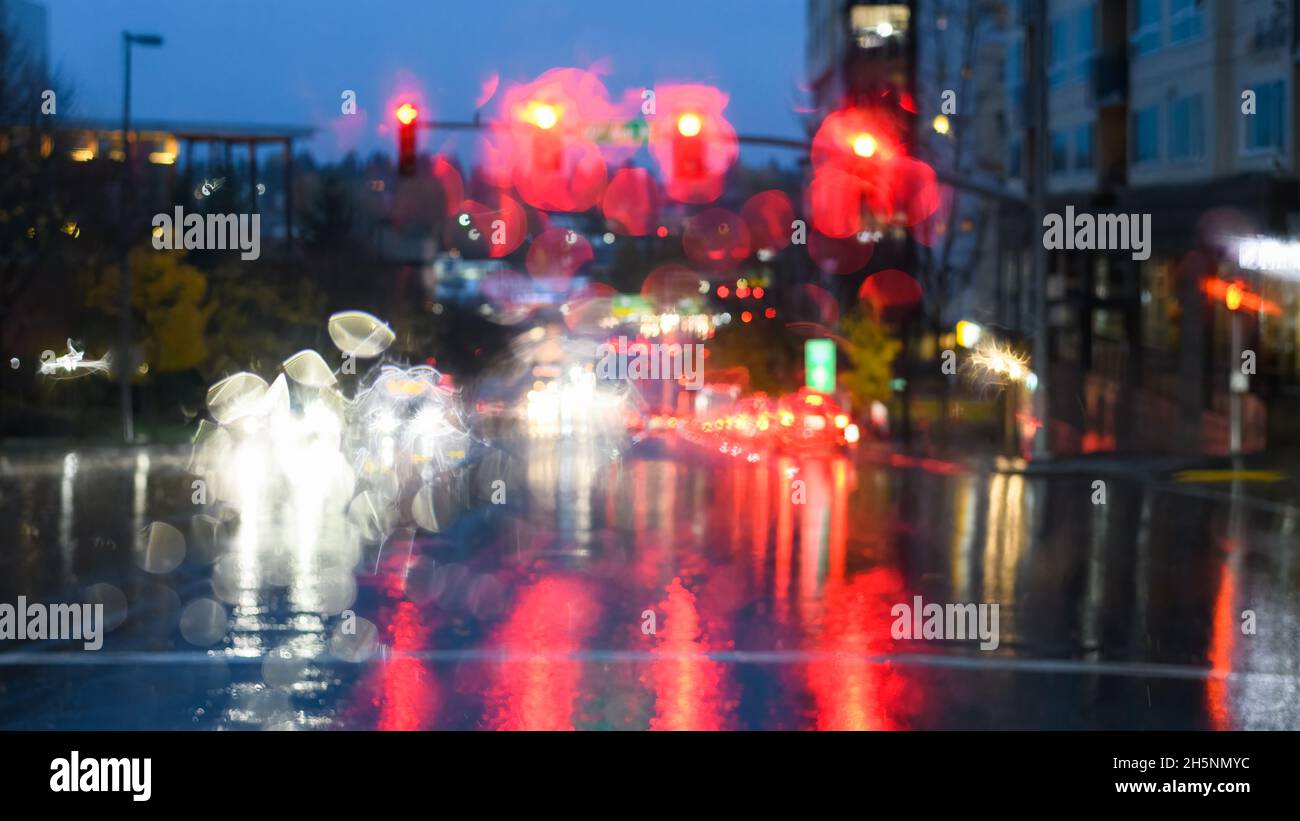 Une forte pluie a masqué les feux de circulation et les phares d'une voiture à un carrefour au crépuscule Banque D'Images
