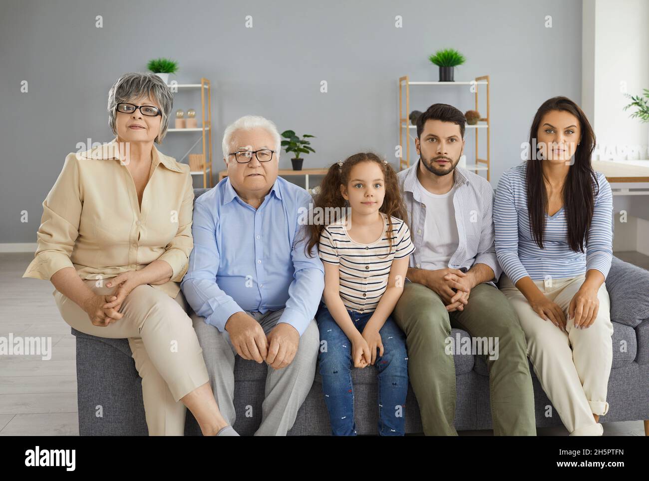 Famille de plusieurs générations assis sur un canapé à la maison et regardant la télévision ensemble Banque D'Images