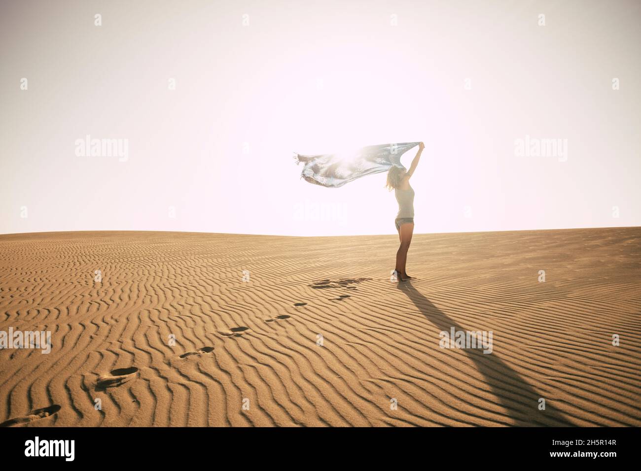 Femme debout contre le soleil sur une dune du désert.Concept de l'homme et de la liberté.Voyage aventure style de vie avec femme mince et ciel lumineux dans backgrou Banque D'Images