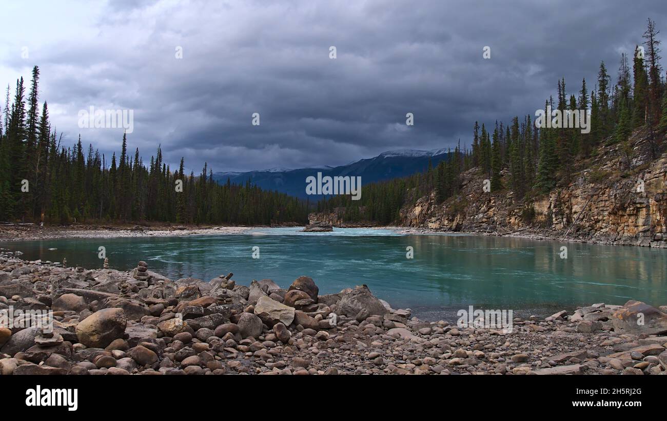 Vue sur la rivière Athabasca dans une vallée des montagnes Rocheuses entourée d'une forêt de conifères avec des pierres en face dans le parc national Jasper, Canada. Banque D'Images