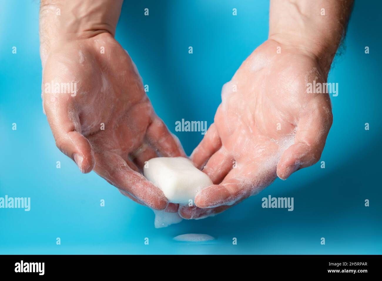 Journée mondiale du lavage des mains, concept d'hygiène personnelle.La main  d'un homme en mousse retient le savon sur un fond bleu Photo Stock - Alamy