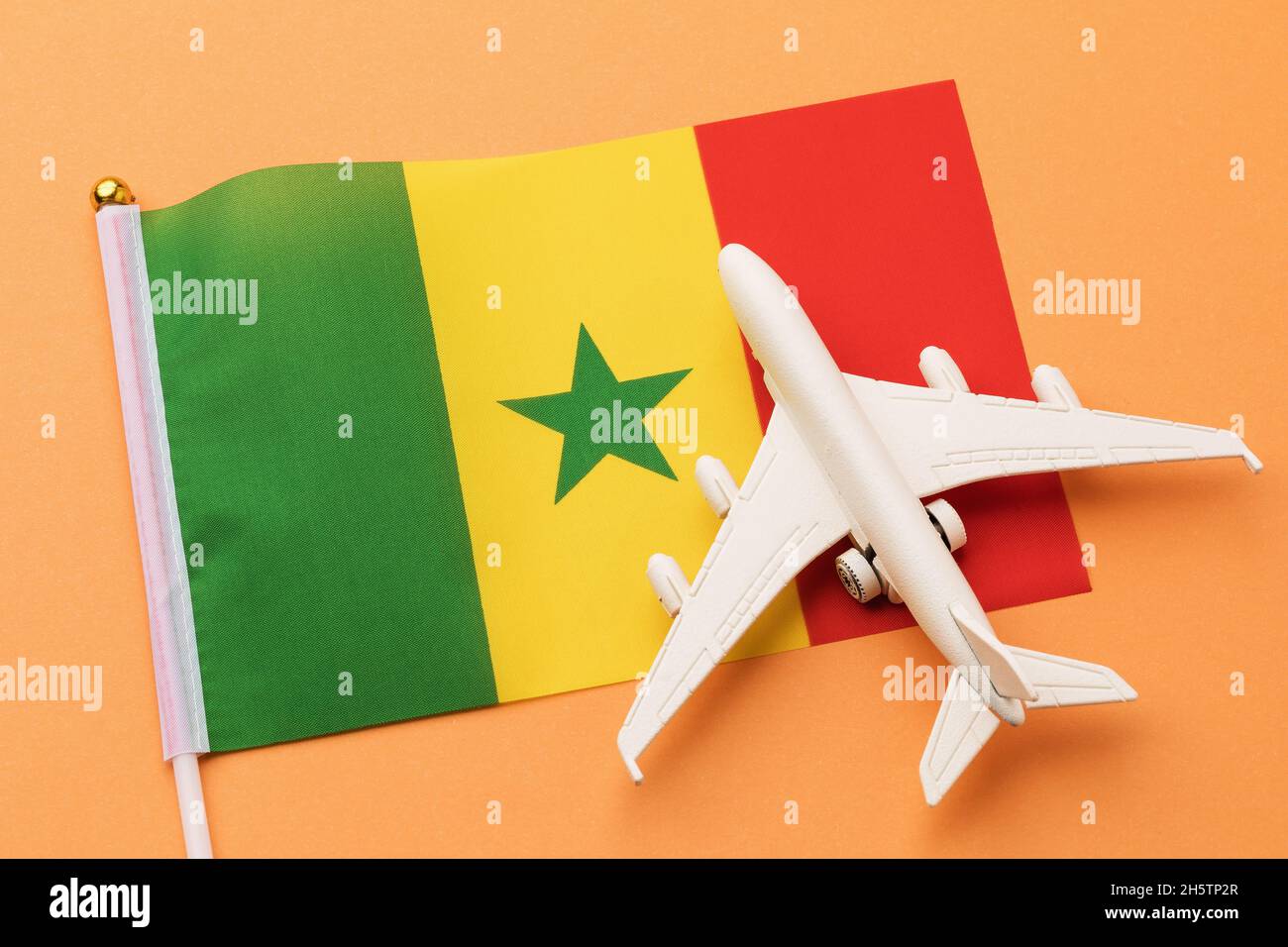 Drapeau du Sénégal et un avion jouet sur fond orange Banque D'Images