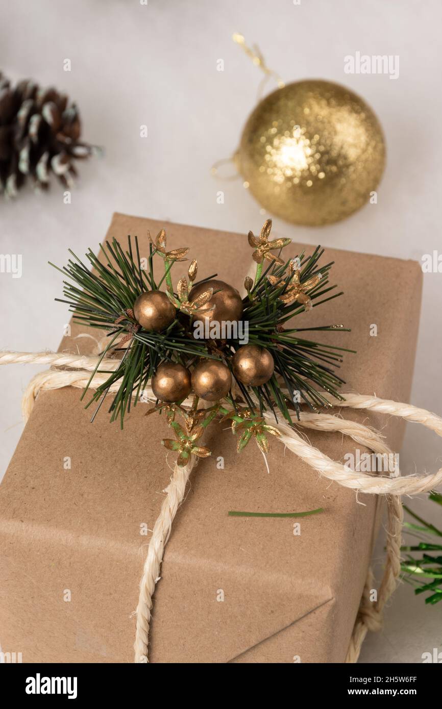 studio avec boîte cadeau enveloppé en papier, avec un noeud avec cordon et un ornement décorant, autour des sphères dorées, avec fond blanc, surprise Banque D'Images