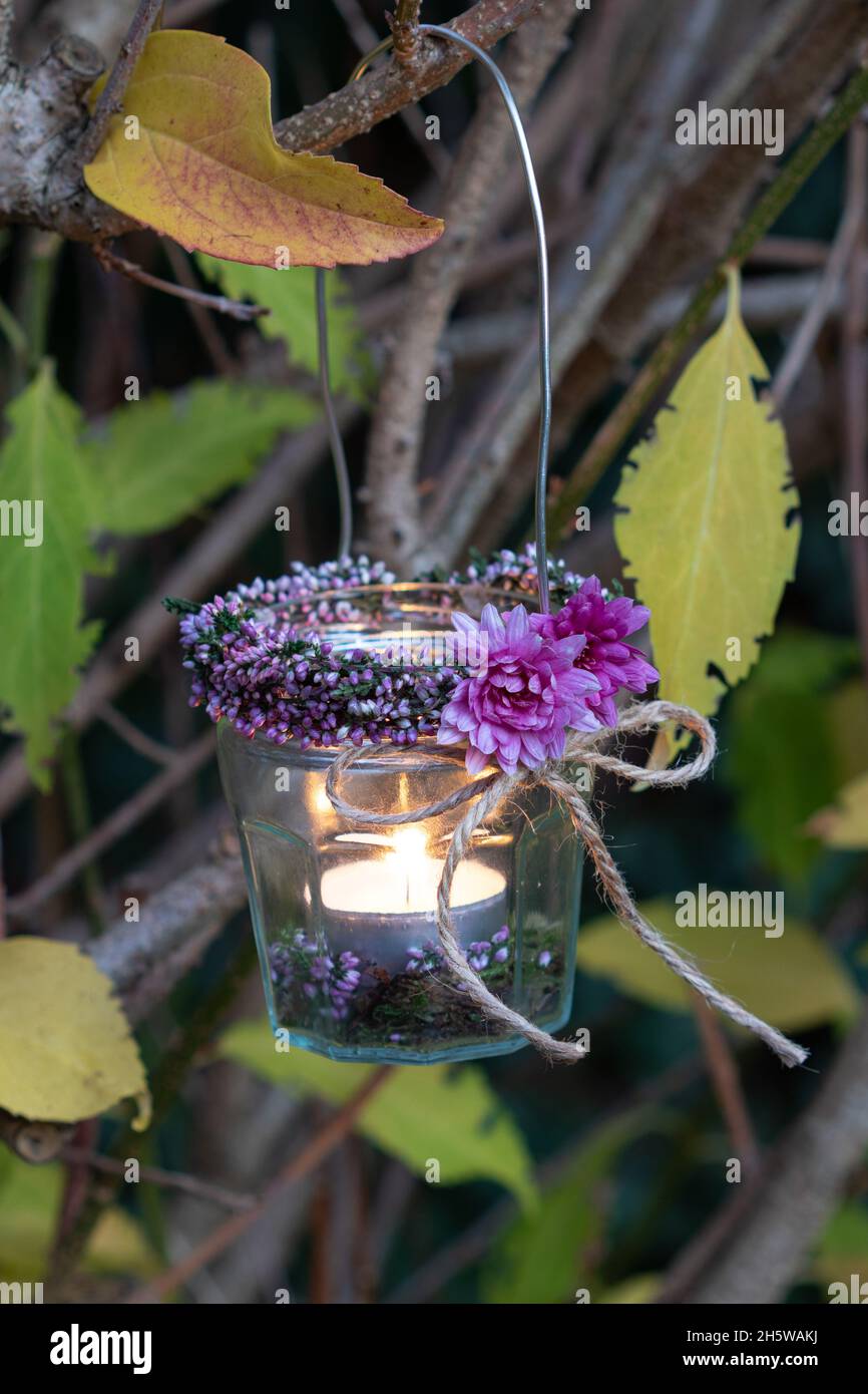 lanterne en verre suspendue décorée de chrysantemums et de fleurs de bruyère Banque D'Images