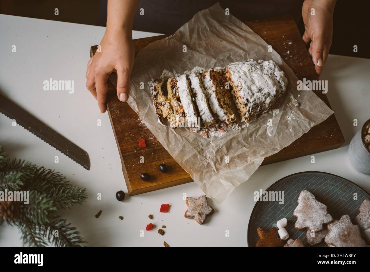 Femme sert des pâtisseries de Noël, stollen sur une planche de bois.Photo d'ambiance de préparation pour les vacances, vue de dessus, mise au point sélective Banque D'Images