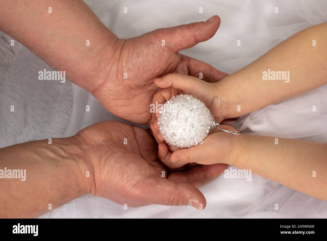 Père et fille tenant une boule de Noël décorative blanche avec soin et amour à la décoration d'un arbre de Noël.Nouvel an et veille de noël Banque D'Images