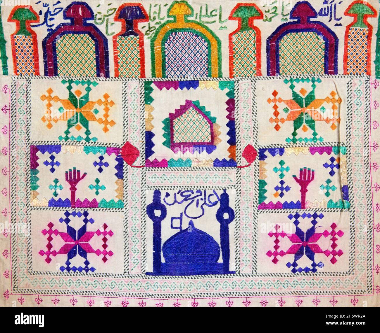 Détail de la toile de pierre de prière Hazara Afghanistan.Tissus brodés avec minaret; mosquée; caractères arabes; motifs de niche de prière.Les toiles de pierre de prière sont utilisées pour tenir la pierre de prière (mohr ou turba) utilisée par les musulmans chiites.Les pierres de prière sont faites d'argile cuite de Karbala.Les pierres de prière sont gardées enveloppées dans les chiffons dans la maison ou sur le corps.Lors de la prière on met le tissu de pierre de prière sur le tapis de prière.Les chiffons et les pierres de prière sont placés sur le tapis de prière de telle manière que l'on touche la pierre avec le front lorsqu'on se plie pendant la prière. Banque D'Images