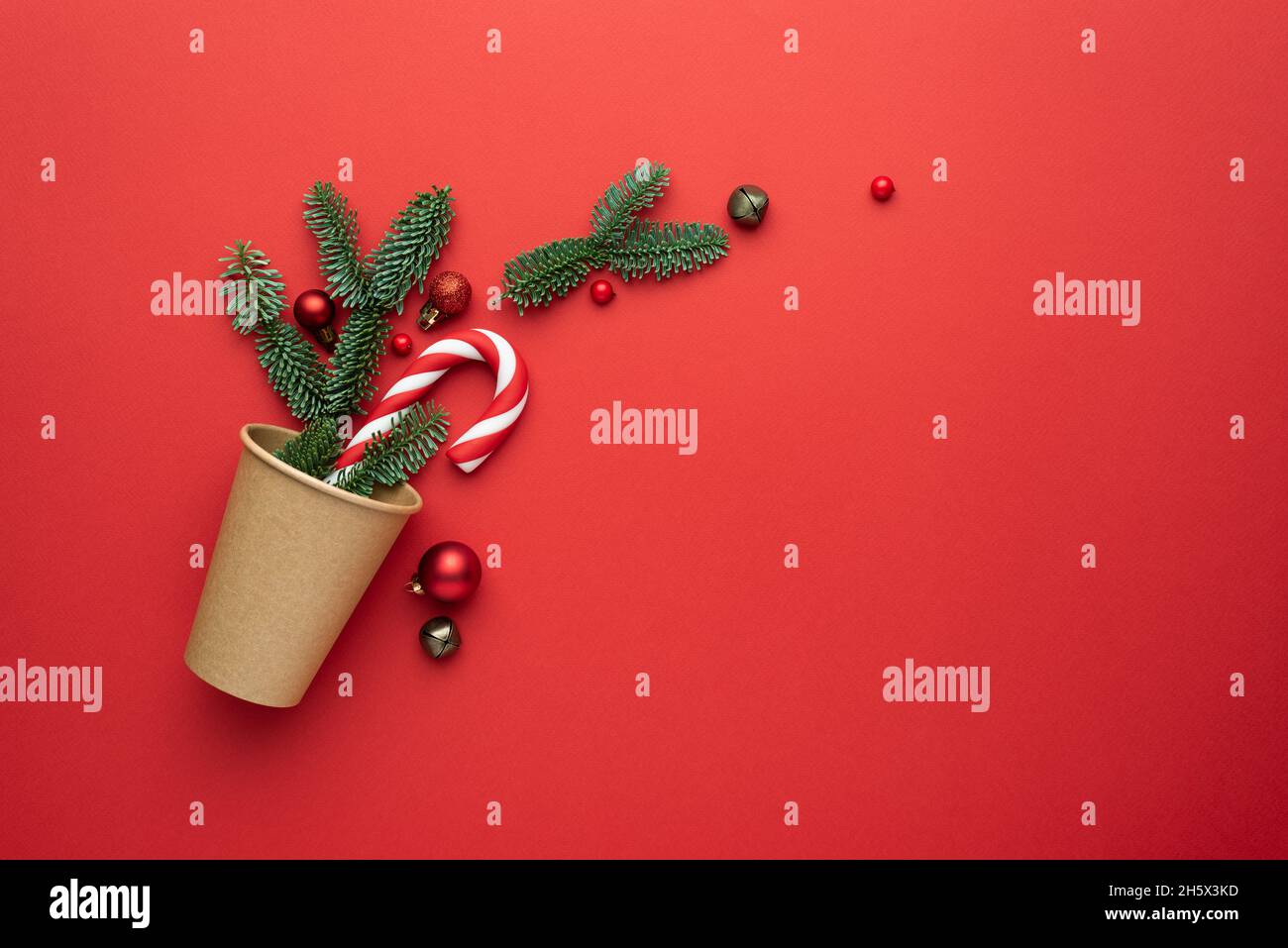 Carte de Noël avec décorations pour arbres, branches en sapin et décor festif sur fond rouge Banque D'Images