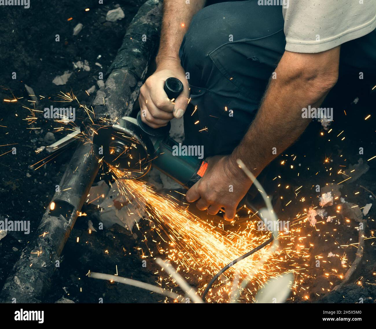 L'employé coupe le tuyau de gaz avec une meuleuse et beaucoup d'étincelles survole. Banque D'Images