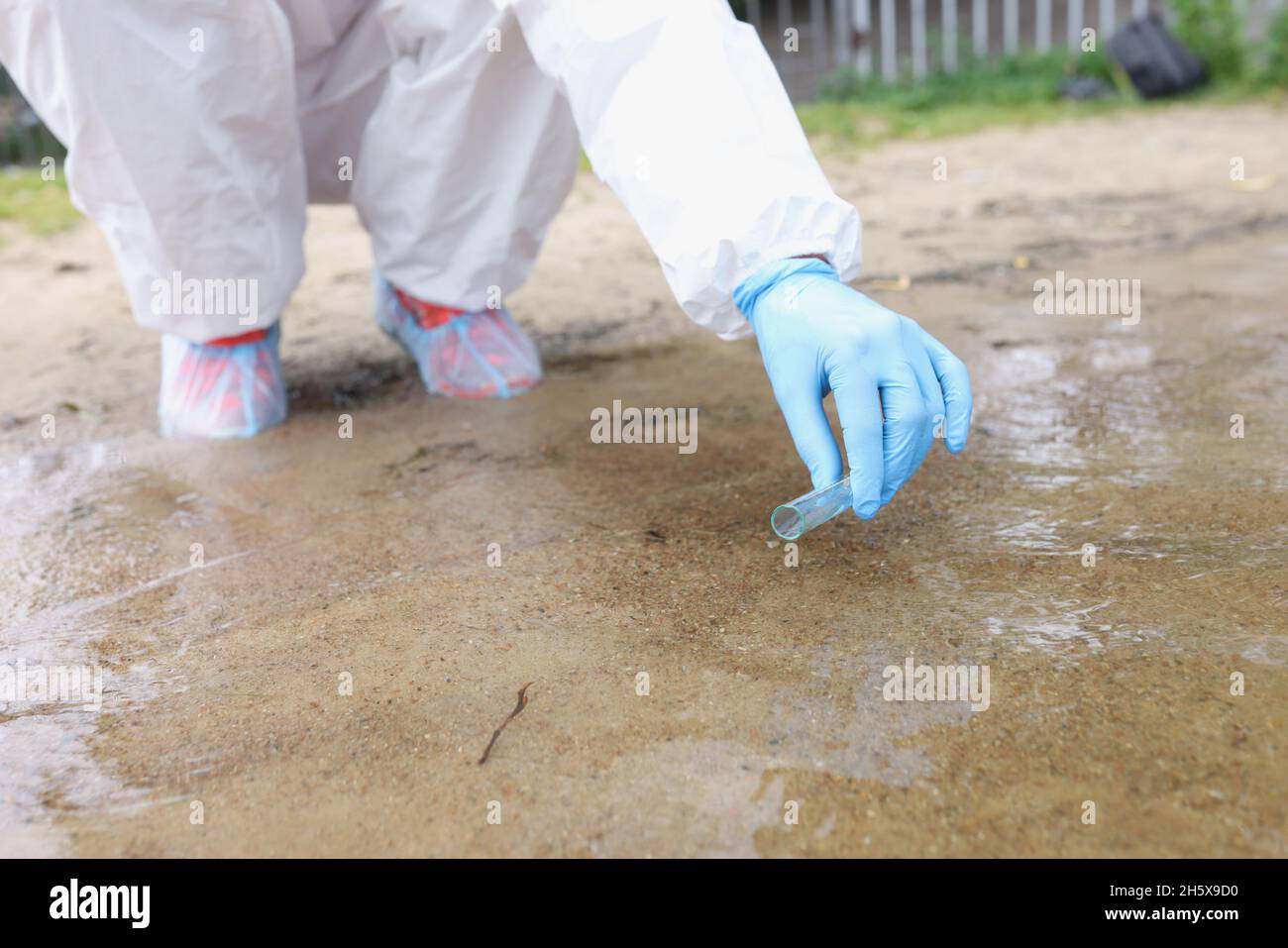 Écologiste en combinaison et gants de protection prenant des échantillons d'eau de la fermeture du lac Banque D'Images