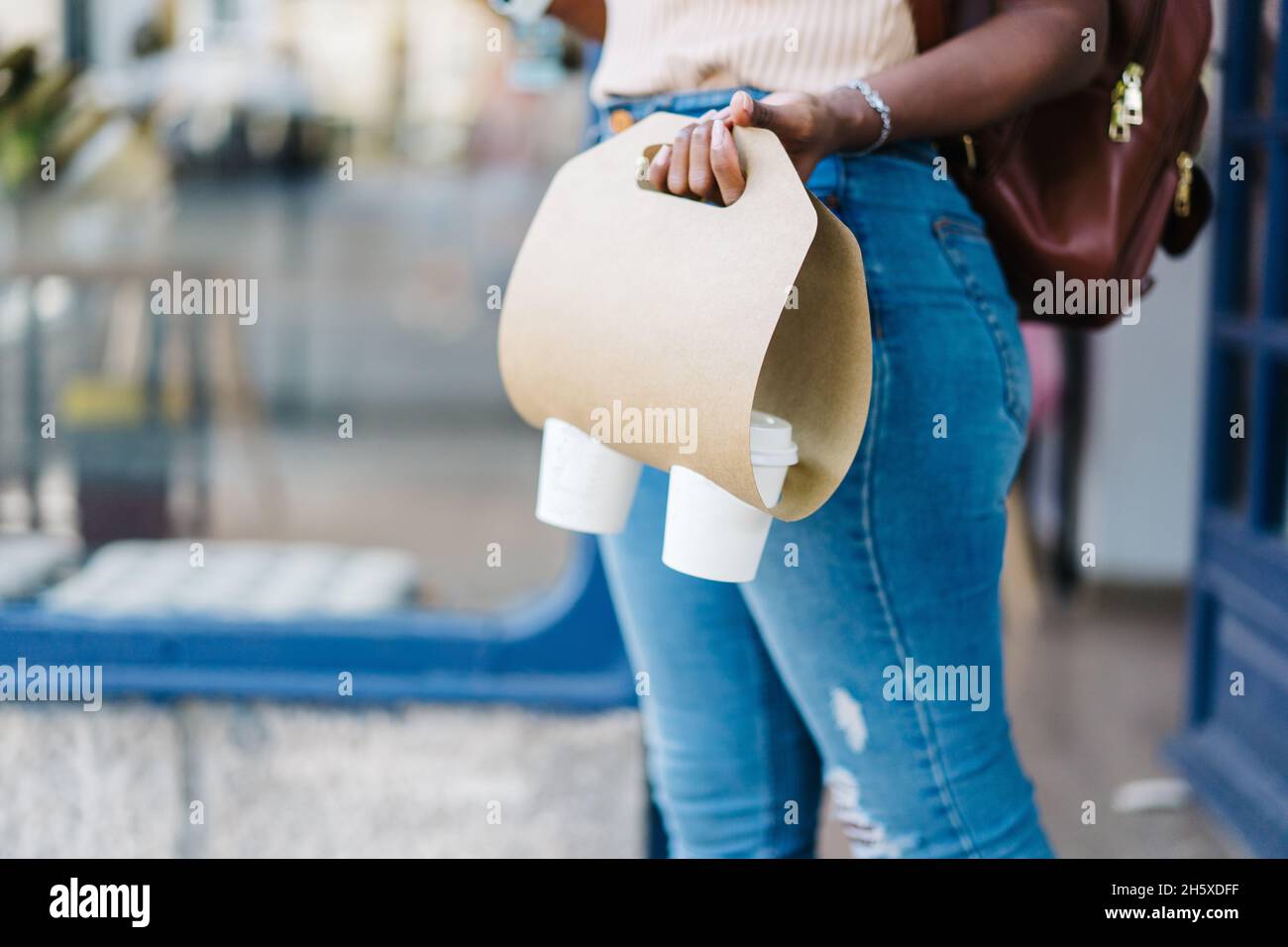 Crop anonyme femme dans des vêtements décontractés et sac à dos debout sur  la rue avec sac en papier avec des tasses à emporter café près du café  Photo Stock - Alamy