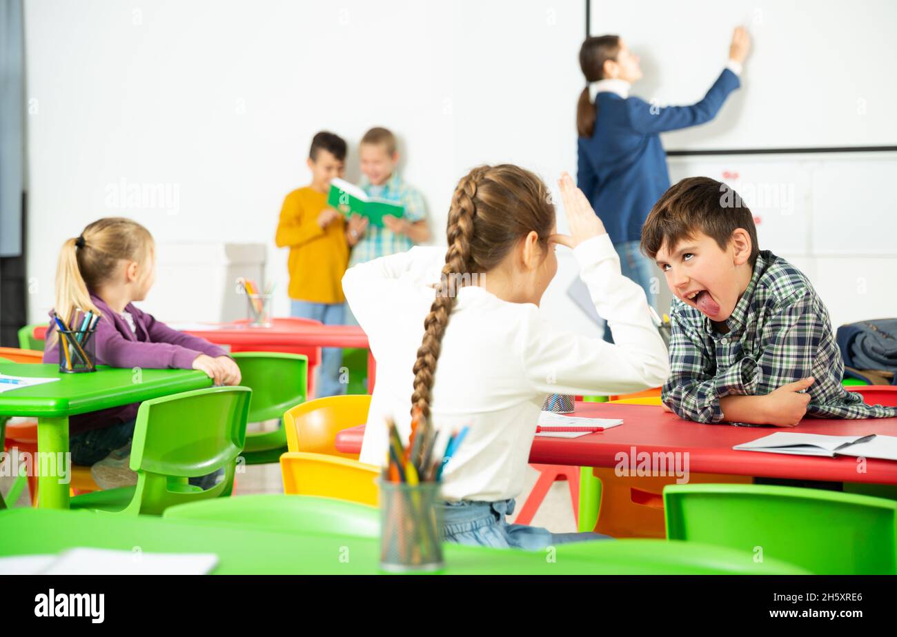 Les élèves heureux assis bavardant à leçon à l'école élémentaire Banque D'Images