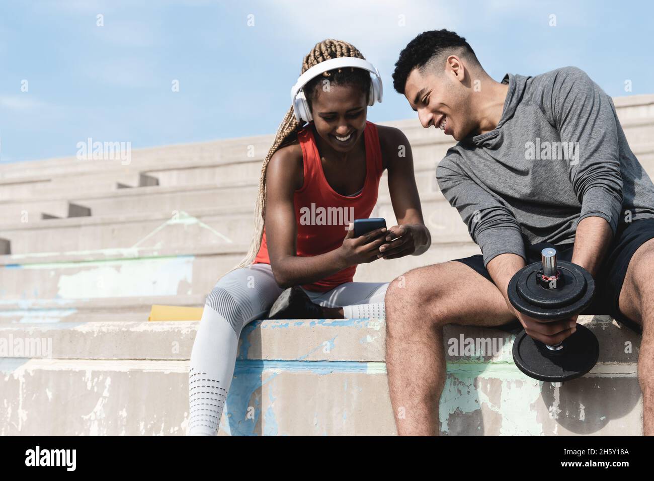 De jeunes amis africains s'amusent en utilisant le téléphone mobile après la routine d'entraînement - se concentrer sur la main tenant dumbbell Banque D'Images