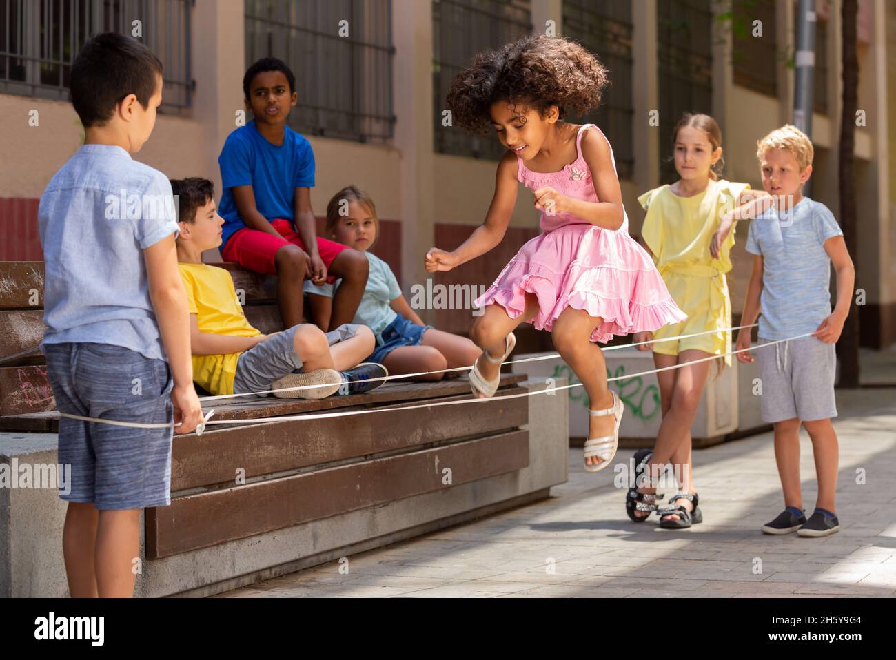 Jeu de saut de petite fille péruvienne par le groupe de caoutchouc avec des amis européens Banque D'Images