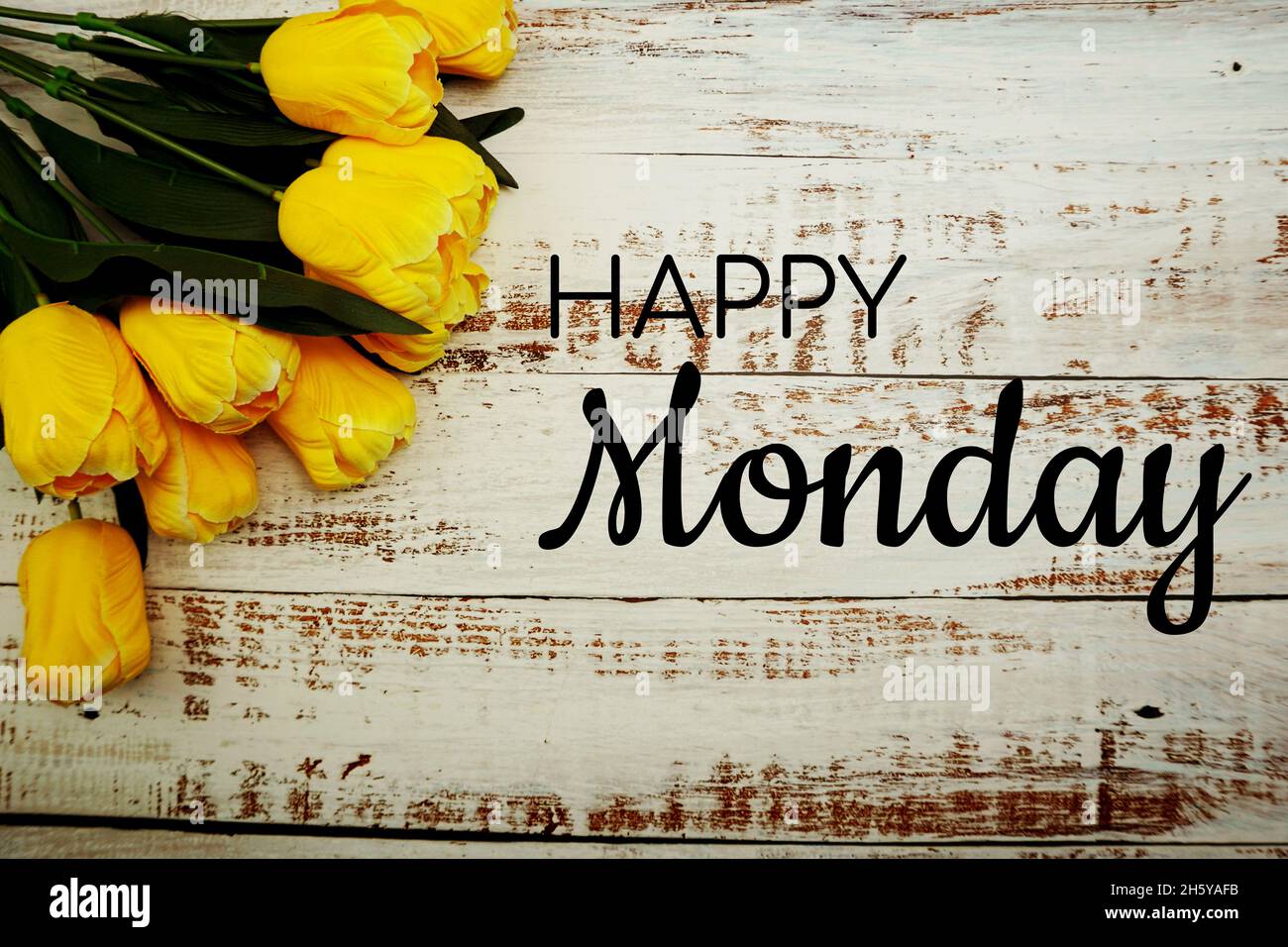 Happy Monday text et bouquet de tulipes jaunes sur fond blanc en bois Banque D'Images