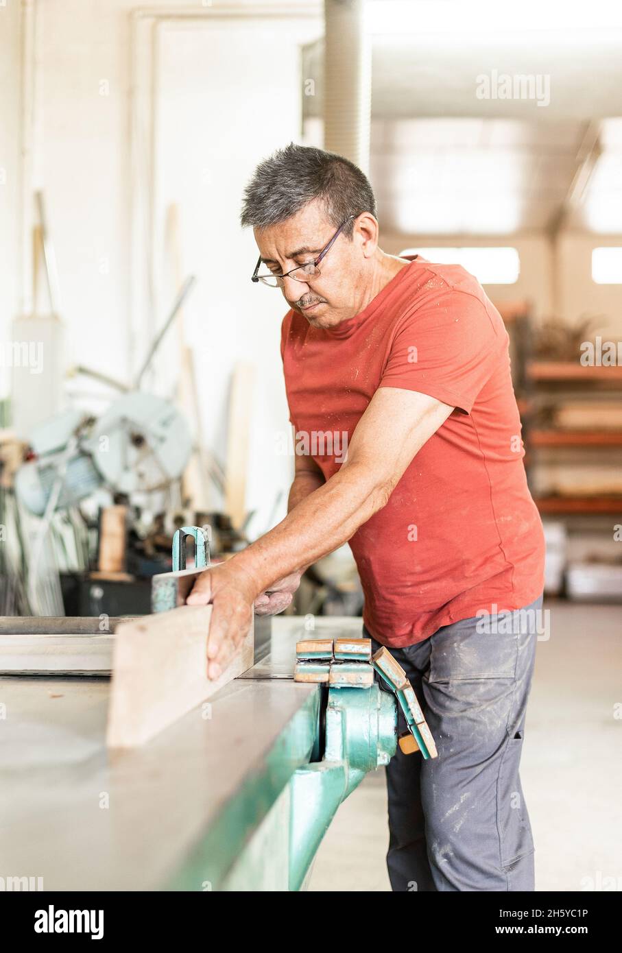 Homme adulte travaillant manuellement avec une machine de rabotage du bois Banque D'Images