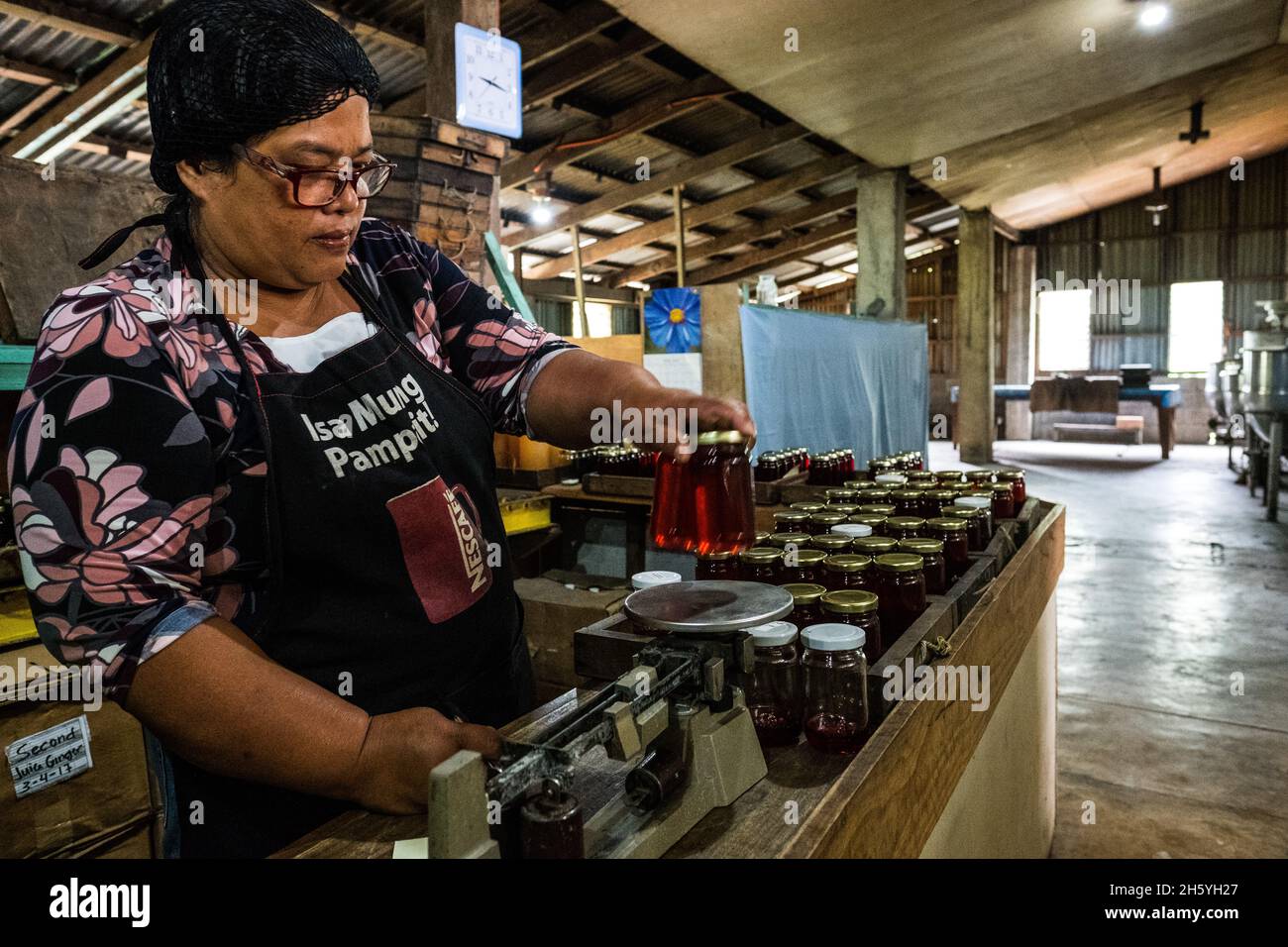 Juillet 2017.Elizabeth Palcay, chef cuisinier, effectue les contrôles de qualité finaux et termine l'emballage de la gelée d'hibiscus.La Kalihan Educational Foundation (KEF) gère une petite confiture, gelée, et d'autres aliments préparés faisant opération dans le cadre de leurs programmes de développement d'entreprise.Imugan, Nueva Vizcaya, Philippines. Banque D'Images