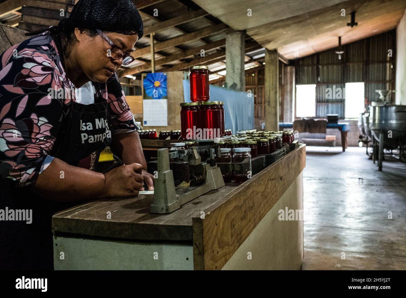 Juillet 2017.Elizabeth Palcay, chef cuisinier, effectue les contrôles de qualité finaux et termine l'emballage de la gelée d'hibiscus.La Kalihan Educational Foundation (KEF) gère une petite confiture, gelée, et d'autres aliments préparés faisant opération dans le cadre de leurs programmes de développement d'entreprise.Imugan, Nueva Vizcaya, Philippines. Banque D'Images