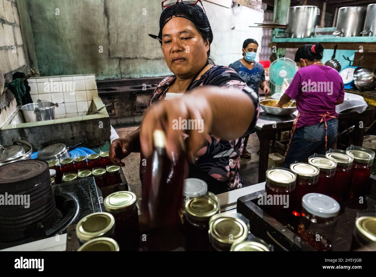 Juillet 2017.Elizabeth Palcay, chef cuisinier, effectue les contrôles de qualité finaux et termine l'emballage de la gelée d'hibiscus.La Kalihan Educational Foundation (KEF) gère une petite confiture, gelée, et d'autres aliments préparés faisant opération dans le cadre de leurs programmes de développement d'entreprise.Imugan, Nueva Vizcaya, Philippines. Banque D'Images