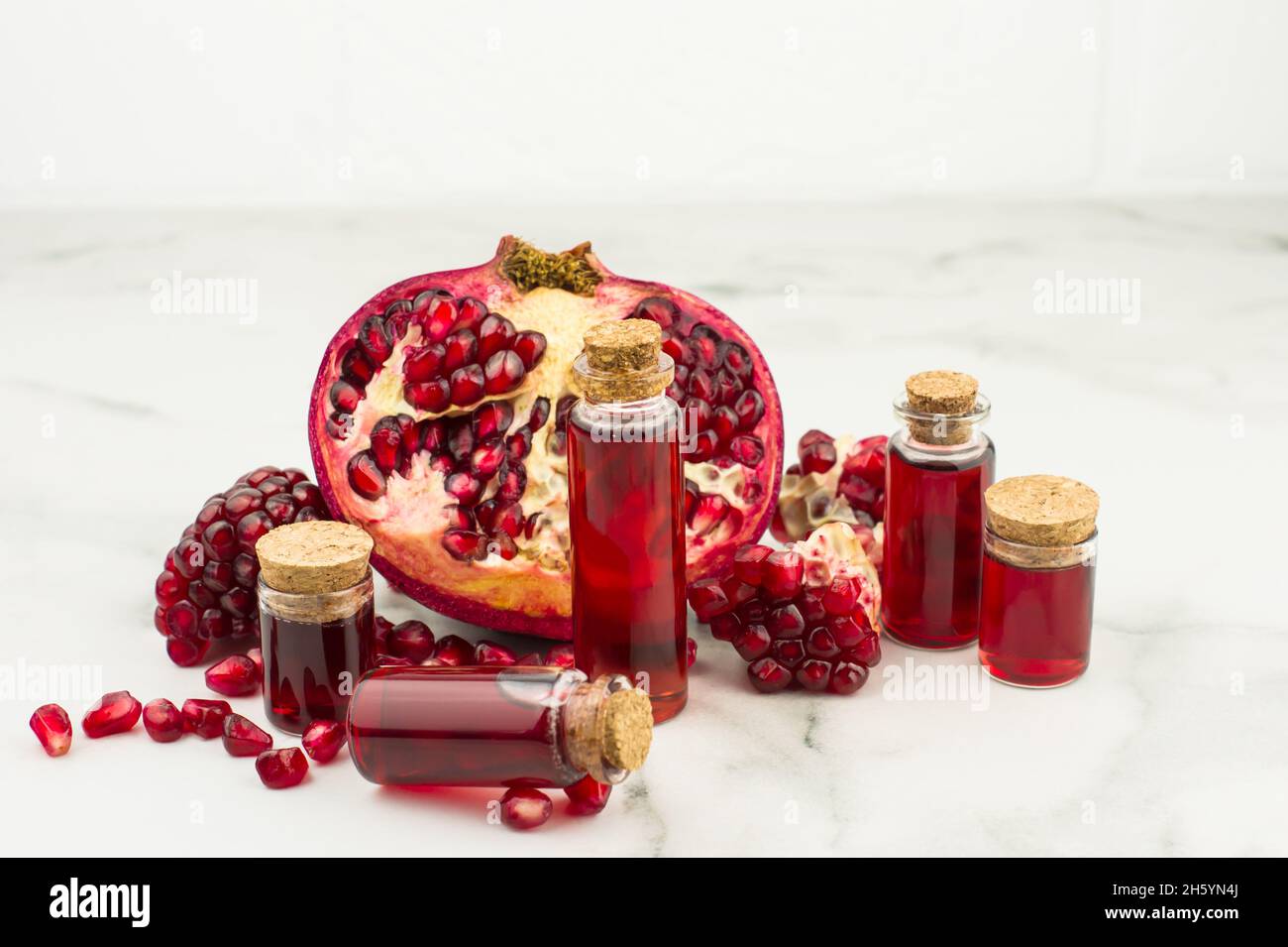 huile de grenade en bouteilles sur le fond du fruit de grenade pour le soin de la peau. cosmétique universel, antioxydant Banque D'Images