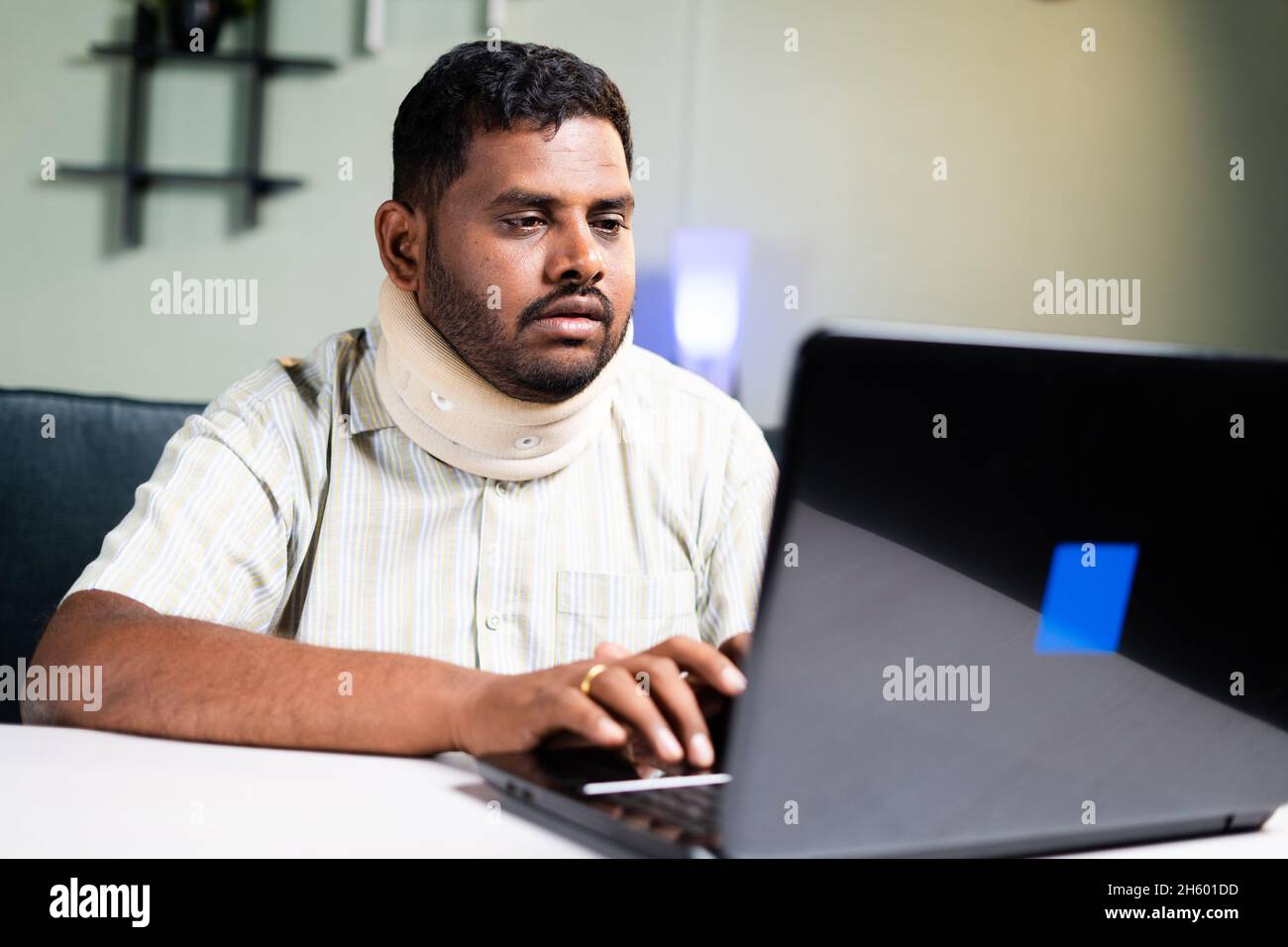 gros homme avec un corset de cou travaillant sur ordinateur portable en raison de douleurs au cou pendant le travail à la maison - concept de travail excessif et des habitudes alimentaires malsaines pendant le coronavirus Banque D'Images