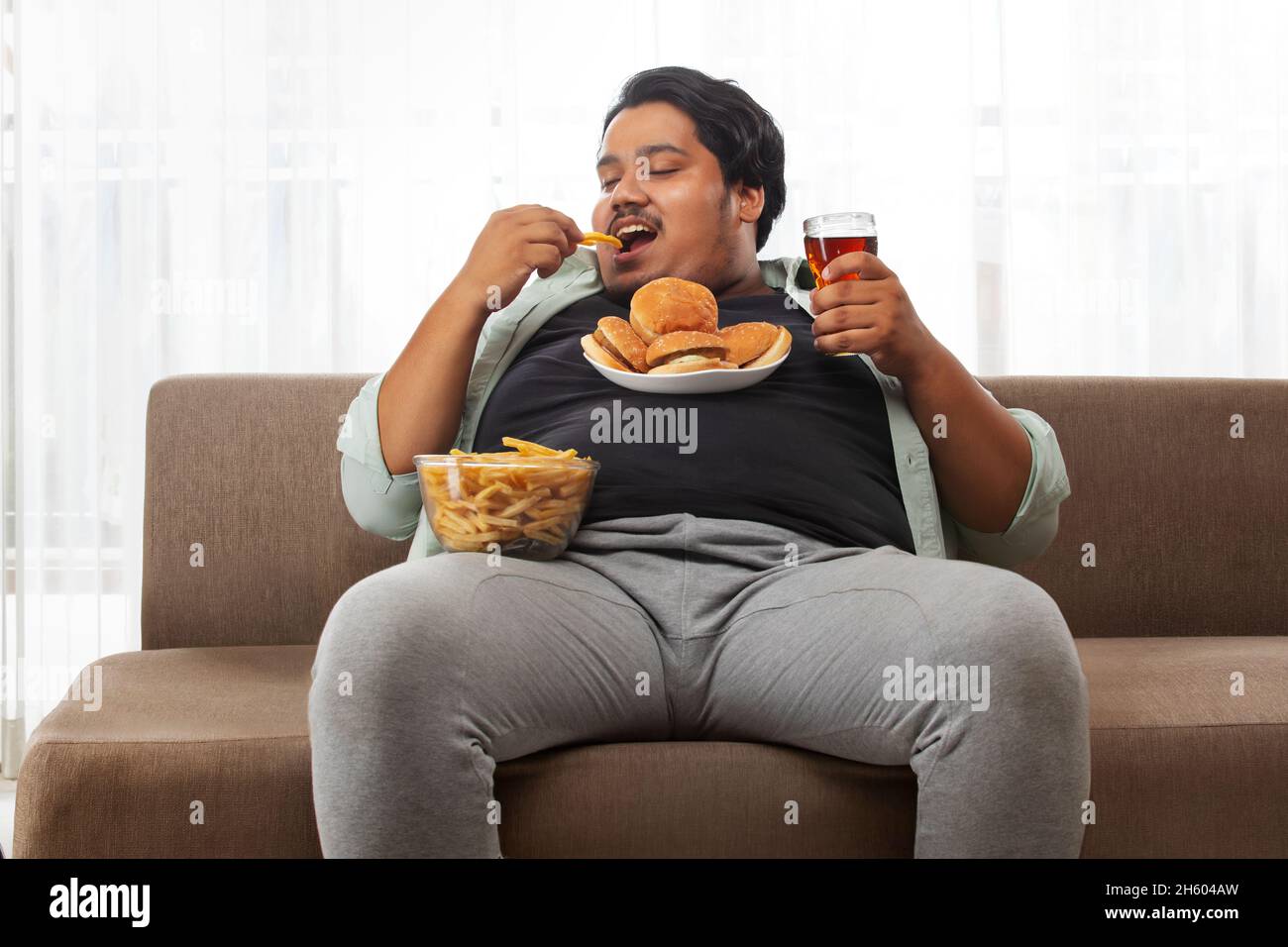 Obese man eating junk food Banque de photographies et d'images à haute  résolution - Alamy