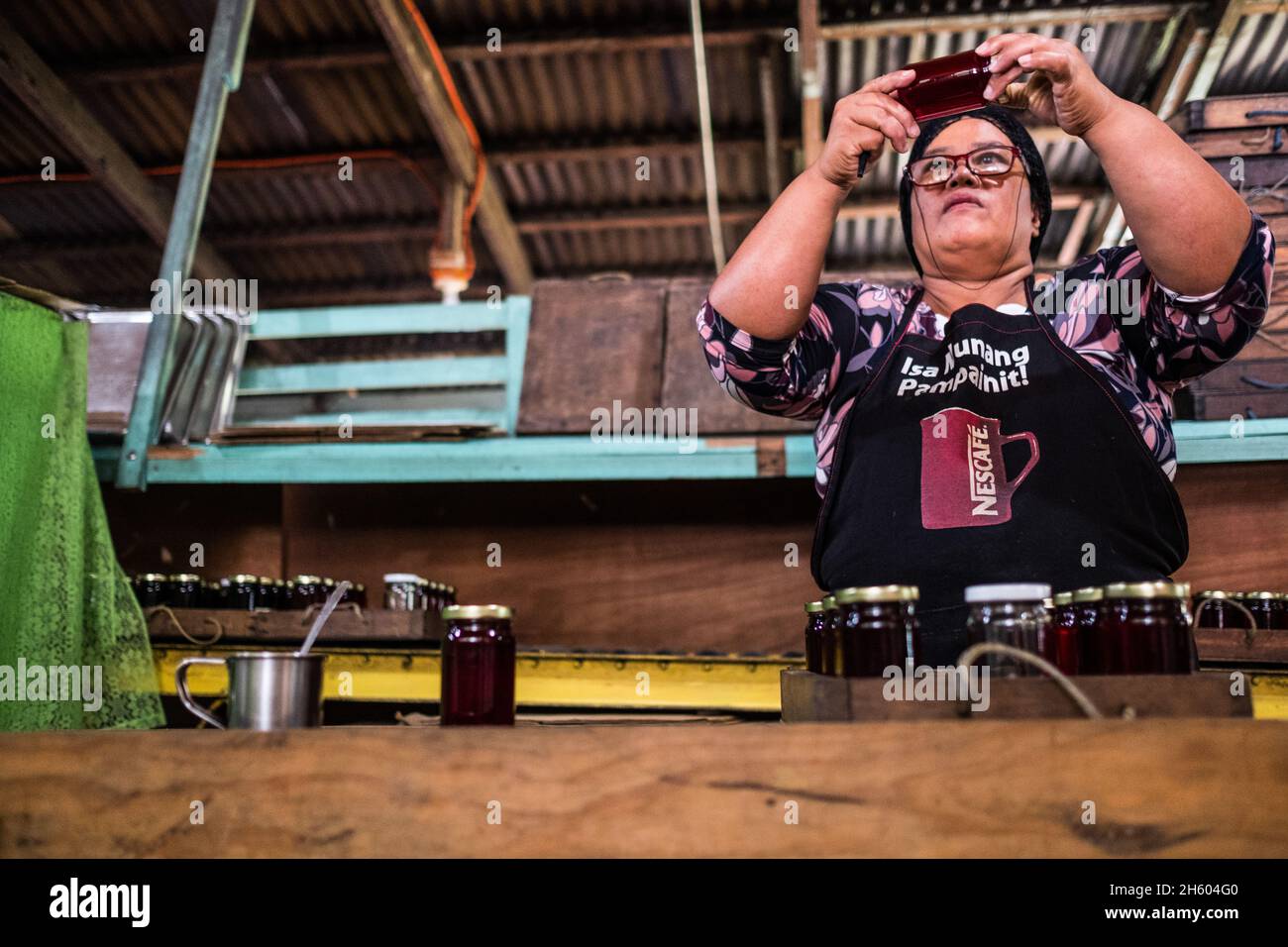 Juillet 2017.Elizabeth Palcay, chef cuisinier, effectue les contrôles de qualité finaux et termine l'emballage de la gelée d'hibiscus.La Kalihan Educational Foundation (KEF) gère une petite confiture, gelée, et d'autres aliments préparés faisant opération dans le cadre de leurs programmes de développement d'entreprise.Imugan, Nueva Vizcaya, Philippines. Banque D'Images