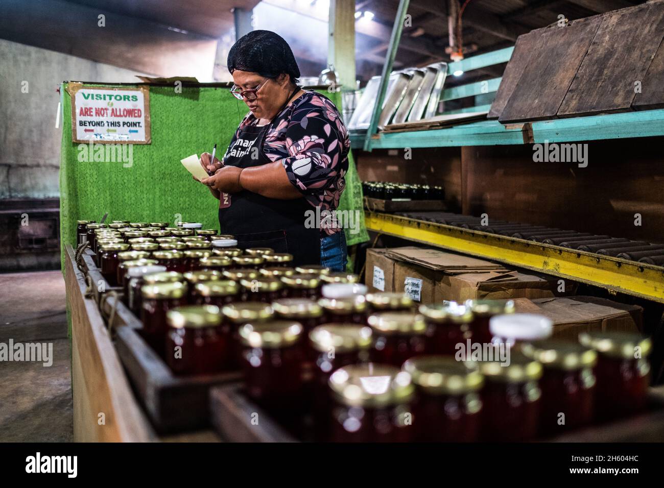 Juillet 2017.Elizabeth Palcay, chef cuisinier, effectue les contrôles de qualité finaux et termine l'emballage de la gelée d'hibiscus.La Kalihan Educational Foundation (KEF) gère une petite confiture, gelée, et d'autres aliments préparés faisant opération dans le cadre de leurs programmes de développement d'entreprise.Imugan, Nueva Vizcaya, Philippines. Banque D'Images