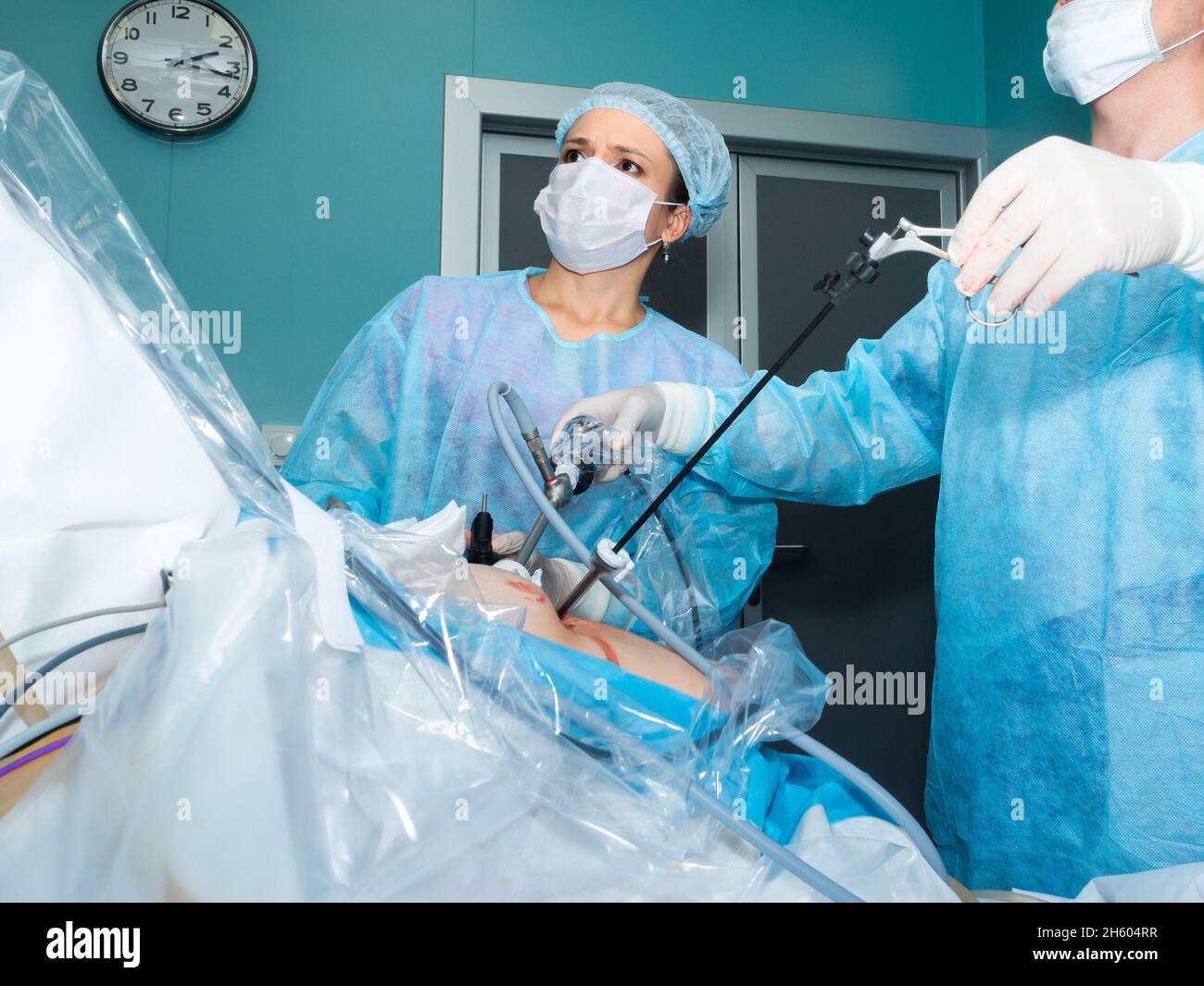 Une femme chirurgien dans un uniforme chirurgical et un masque de protection effectue une opération laparoscopique.Le médecin regarde de près le moniteur pendant la chirurgie.Mise au point sélective. Banque D'Images