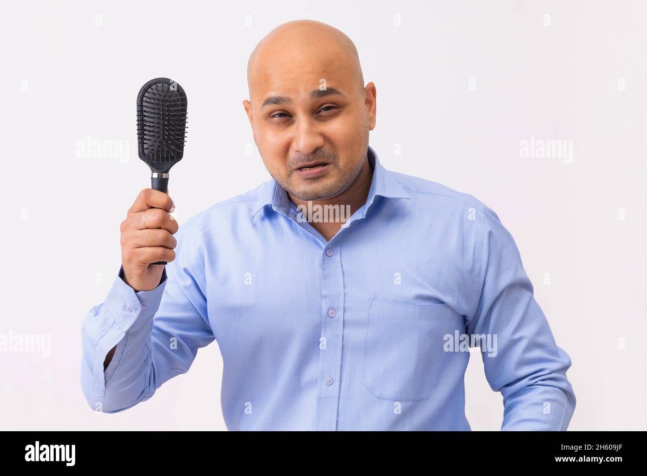 Portrait d'un homme chauve avec tête rasée tenant le peigne avec frustration sur fond blanc. Banque D'Images