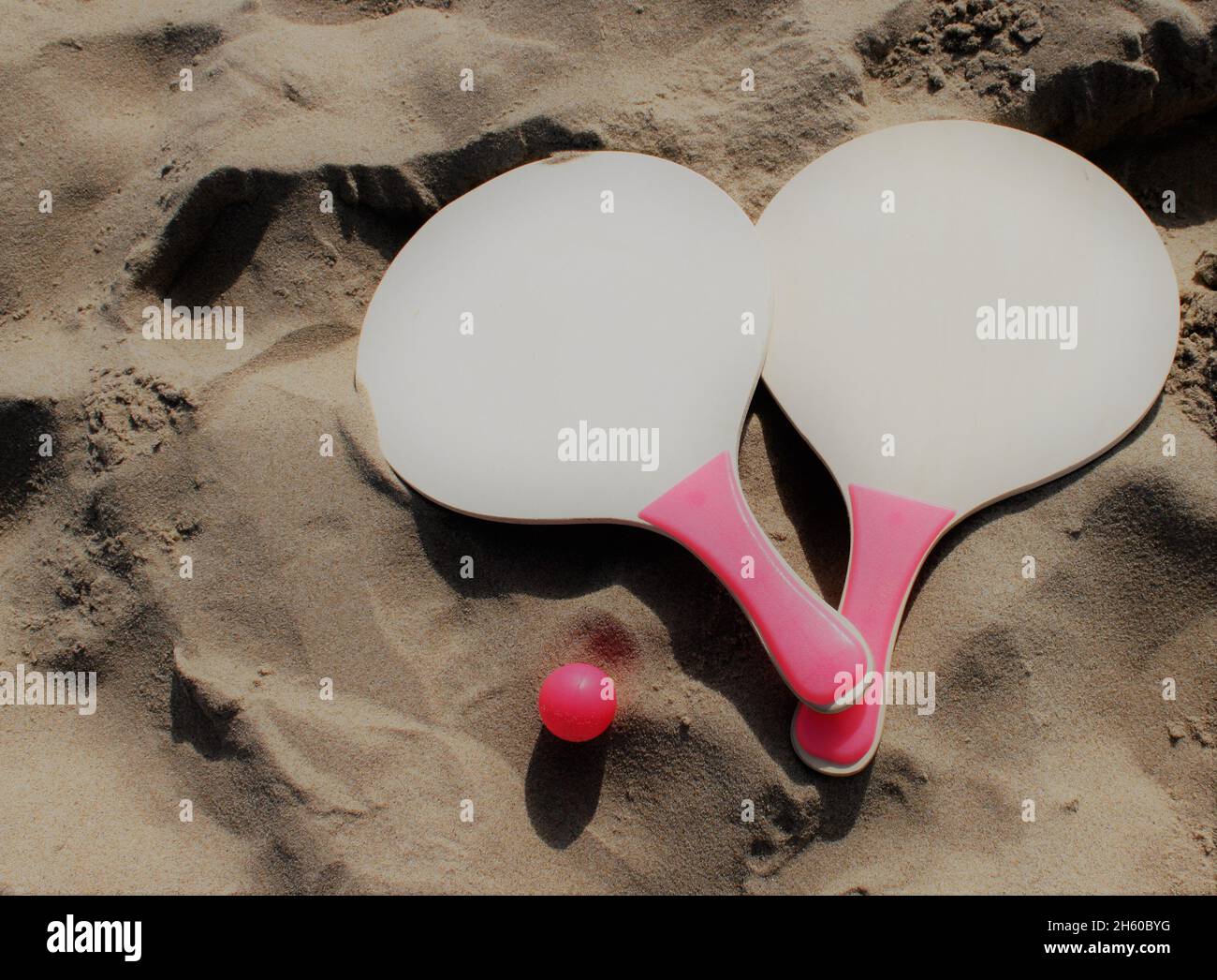 Les raquettes et la balle d'un ensemble de tennis de plage se trouvent dans le sable de la plage Banque D'Images