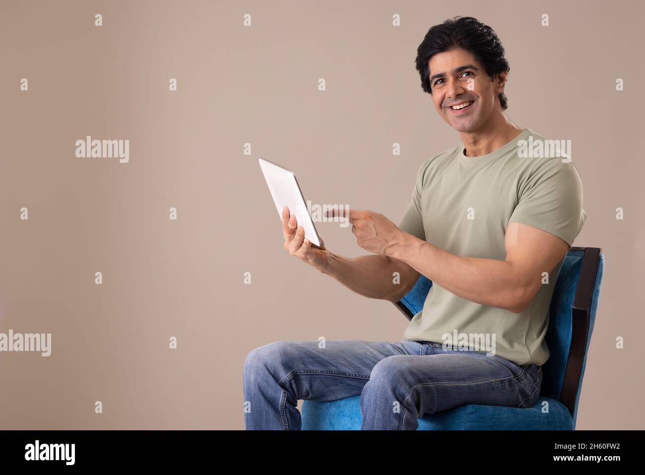Un Indien heureux qui se pose devant l'appareil photo tout en tenant une tablette Banque D'Images