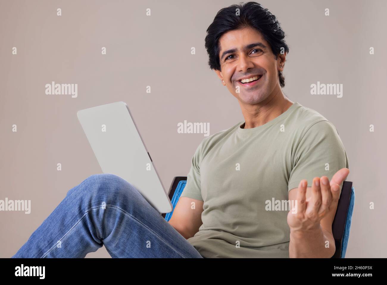 Un Indien heureux qui se pose devant l'appareil photo tout en tenant une tablette Banque D'Images