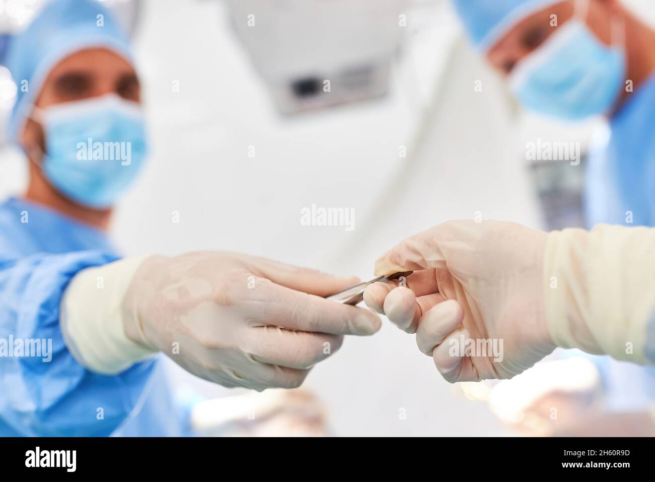 Le médecin résident avec des gants jetables donne le scalpel à ses collègues pendant une opération d'urgence Banque D'Images