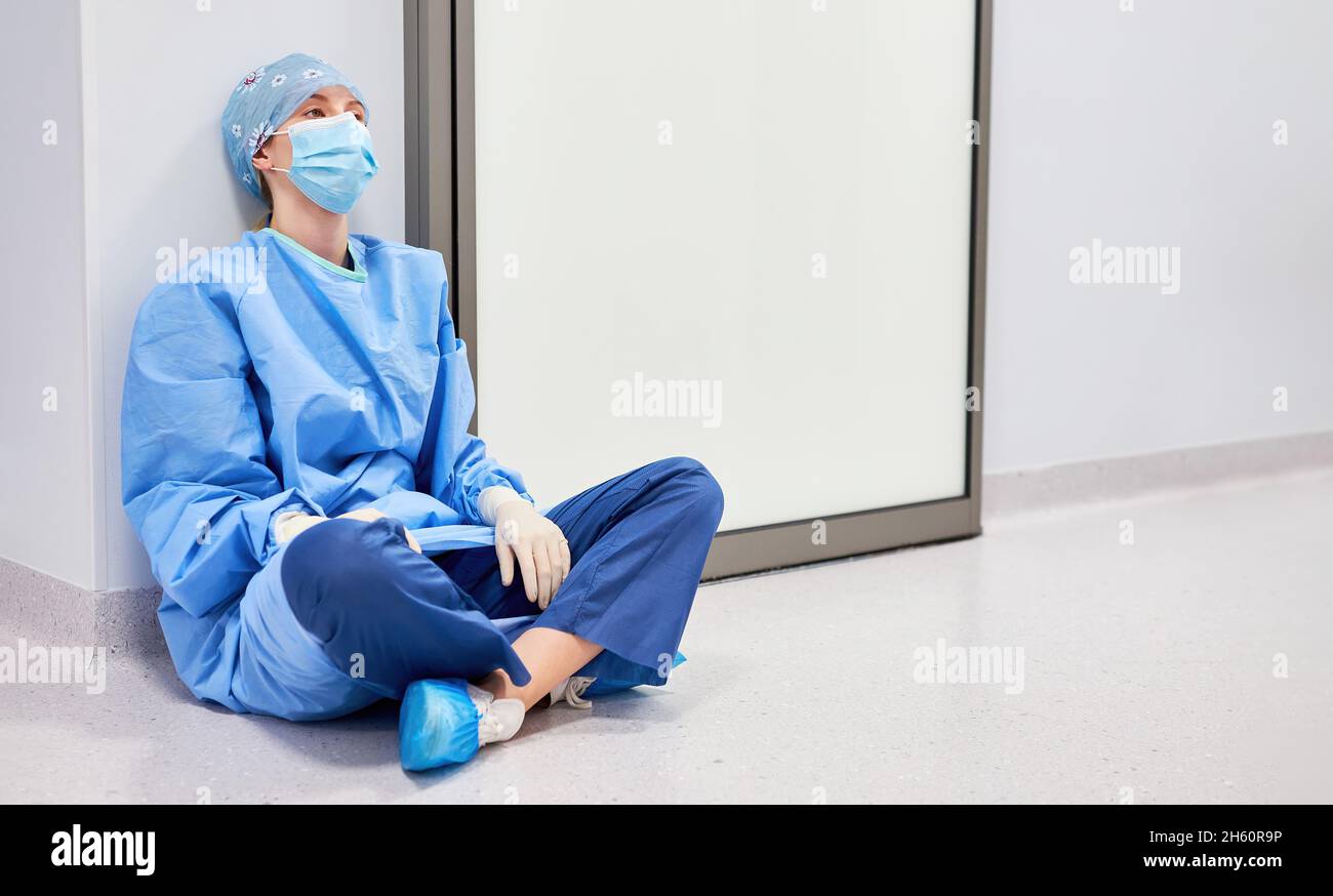 Une infirmière ou un médecin épuisé assis sur le sol dans la salle des urgences de la clinique Banque D'Images
