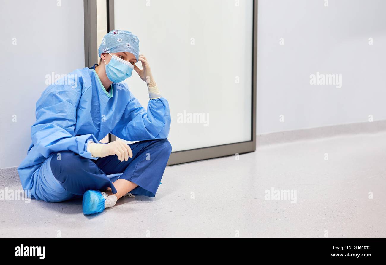 L'infirmière ou l'infirmière est fatiguée et réfléchie devant l'unité de soins intensifs de la clinique Banque D'Images