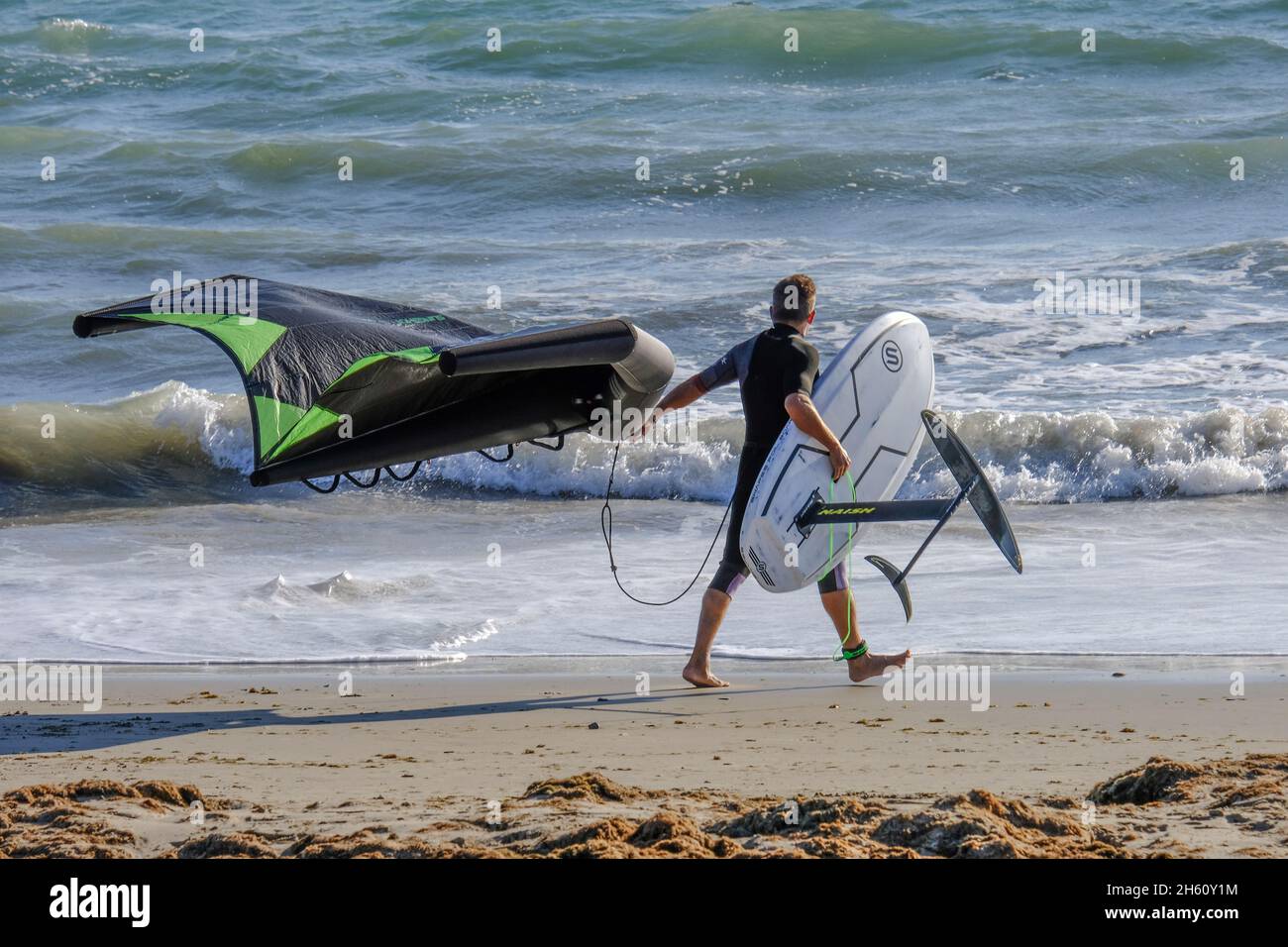 Kite foil surfeur marchant sur la plage de Los Lances avec son cerf-volant et son hydroptère, Tarifa, Costa de la Luz, province de Cadix, Andalousie, Espagne Banque D'Images