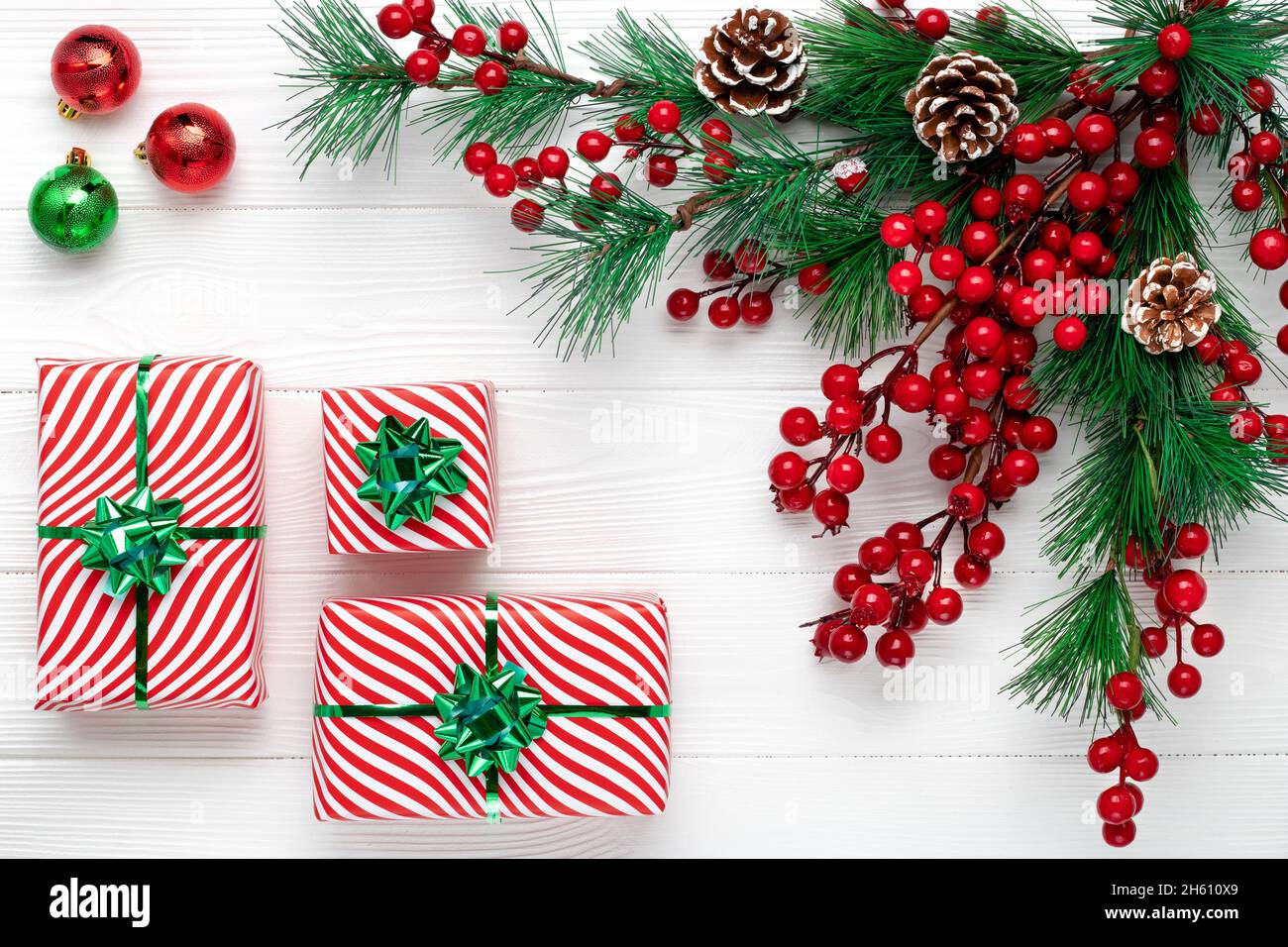 Carte de vœux de Noël avec couronne de branches de pin et cadeaux dans l'emballage.Fond de nouvel an avec branches de sapin, cônes et baies de houx rouges.Festi Banque D'Images