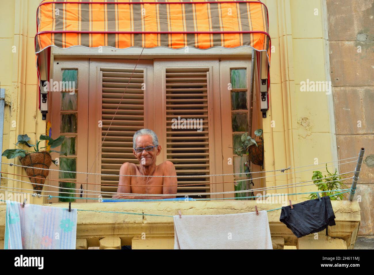 Un homme assis sur un balcon donnant sur Calle Neptuno dans le centre de la Havane, la Habana (la Havane), Habana, Cuba Banque D'Images