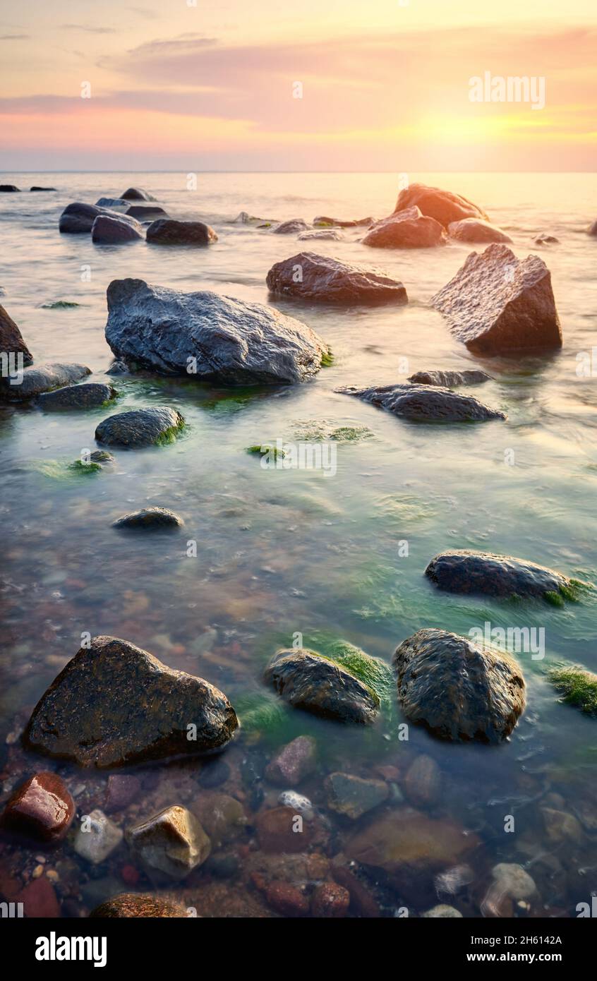Rocky plage de la mer Baltique au coucher du soleil. Banque D'Images