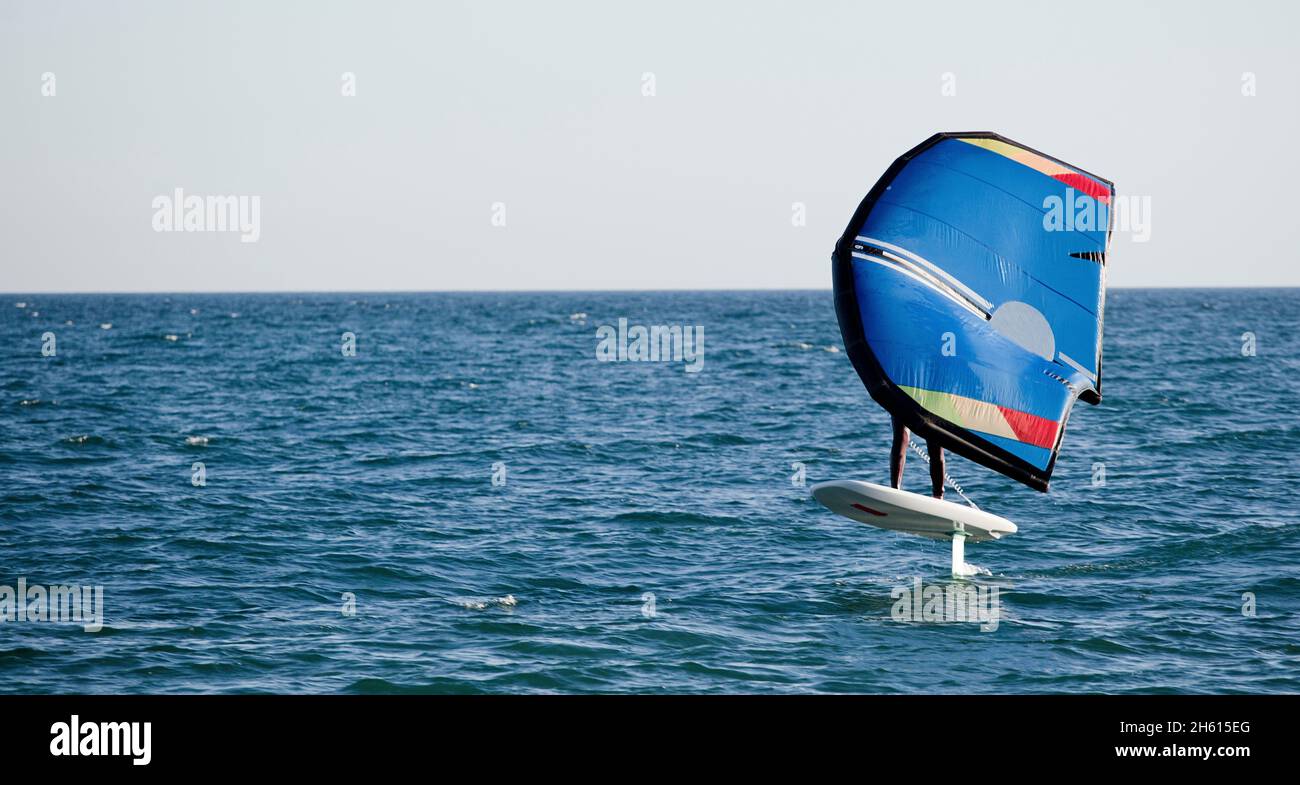 Un homme quitte la plage d'El Palo à Malaga, à bord d'un paddle-board avec hydroptère. Banque D'Images