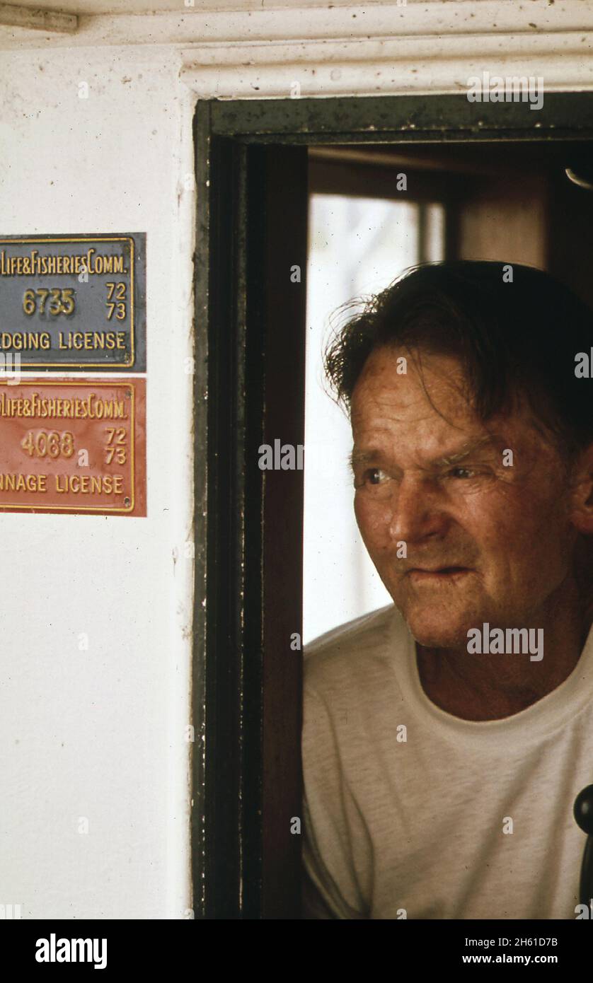 Le capitaine d'un ostréicole du lac Borgne regarde de son pilothouse; Louisiane ca.Juin 1973 Banque D'Images