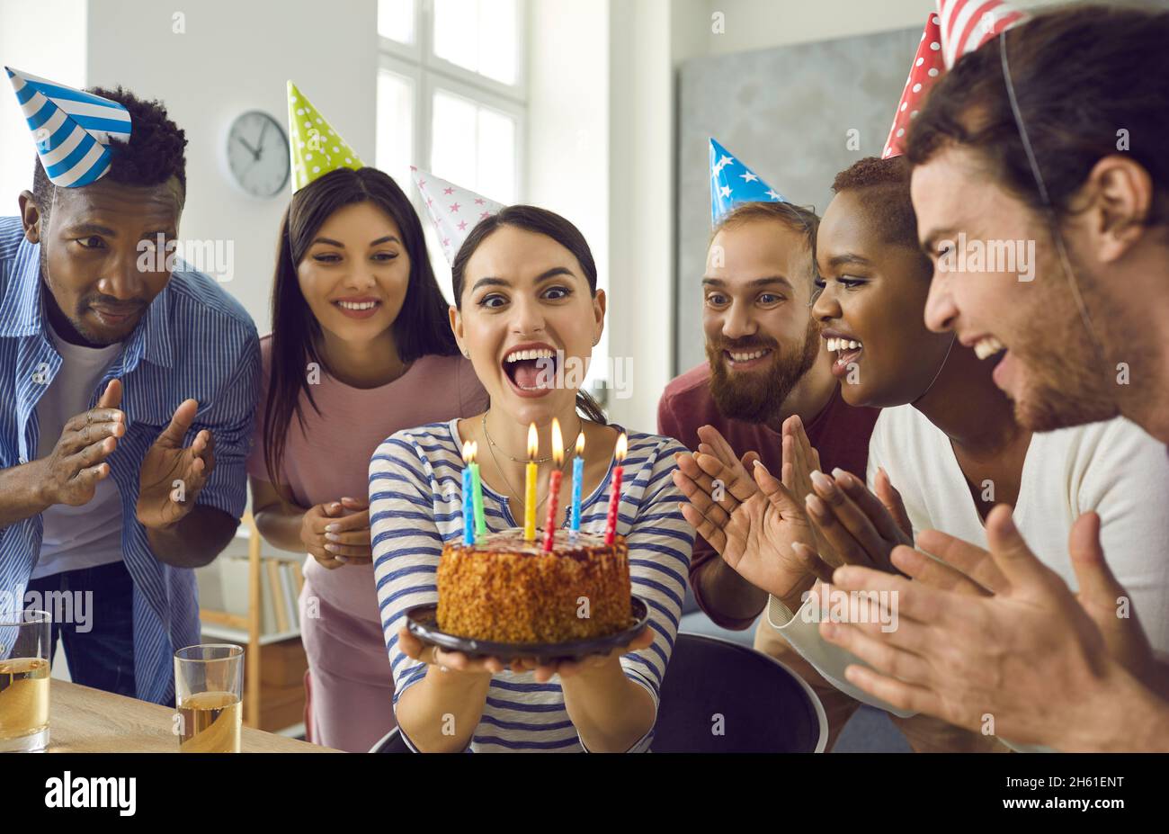 Une femme entourée de ses amis fait un souhait et va souffler les bougies sur le gâteau. Banque D'Images