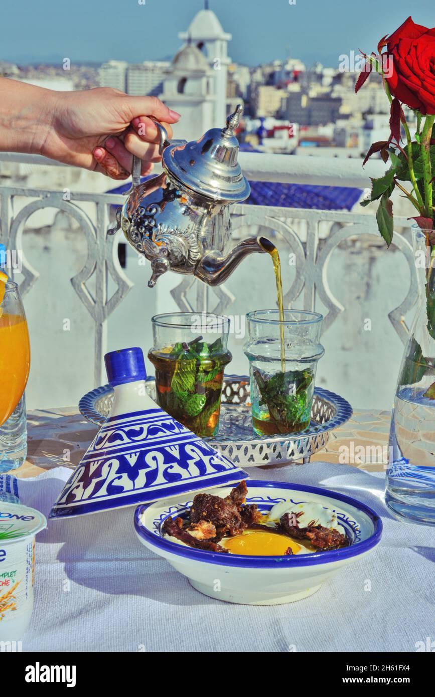une femme tenant à la main argent théière vintage et versant le thé marocain sucré à la menthe traditionnel.Hospitalité et service arabes. Banque D'Images