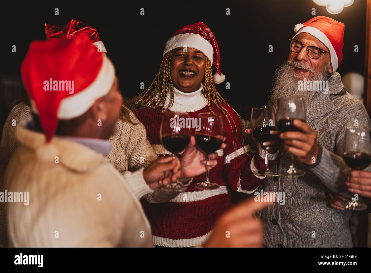 De joyeux amis senior célébrant les vacances de Noël tout en dégustant du rouge verres à vin sur le patio de la maison fête Banque D'Images