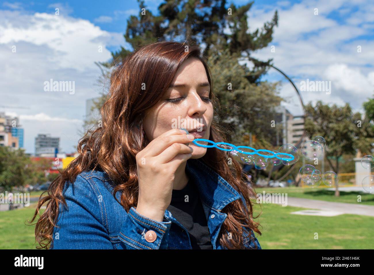 Vue rapprochée d'une belle femme hispanique qui soufflait de bulles de savon au milieu d'un parc le matin ensoleillé Banque D'Images