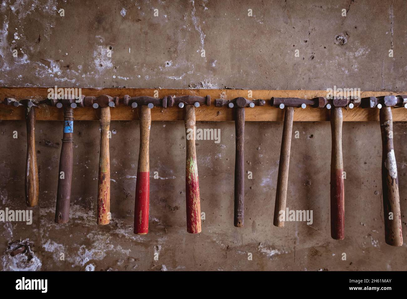 Divers marteaux suspendus côte à côte sur un support à crochet monté au mur dans l'industrie Banque D'Images