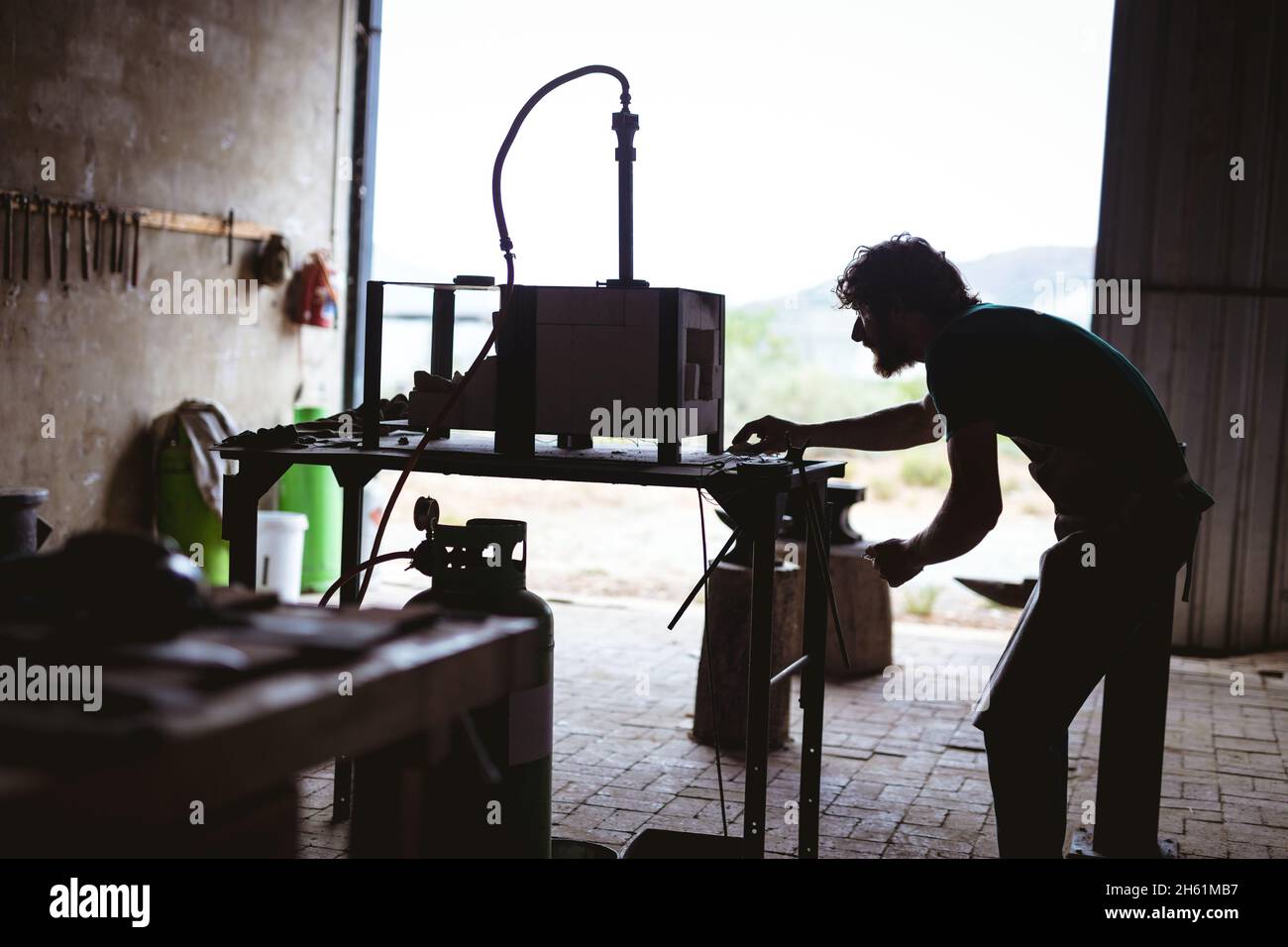 Vue latérale du forgeron travaillant sur des machines dans l'industrie manufacturière Banque D'Images